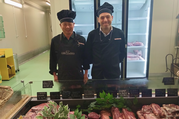 Due macellai in divisa dietro il banco di carne in una macelleria del Comprensorio