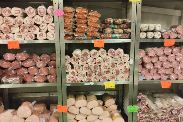 Scaffali pieni di salumi confezionati in un deposito refrigerato
